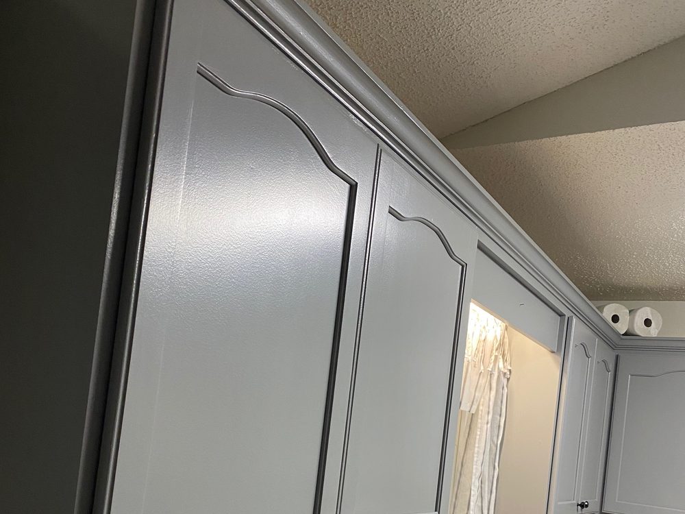 A close view of painted kitchen wall cabinets with arched door panels and dark round knobs.