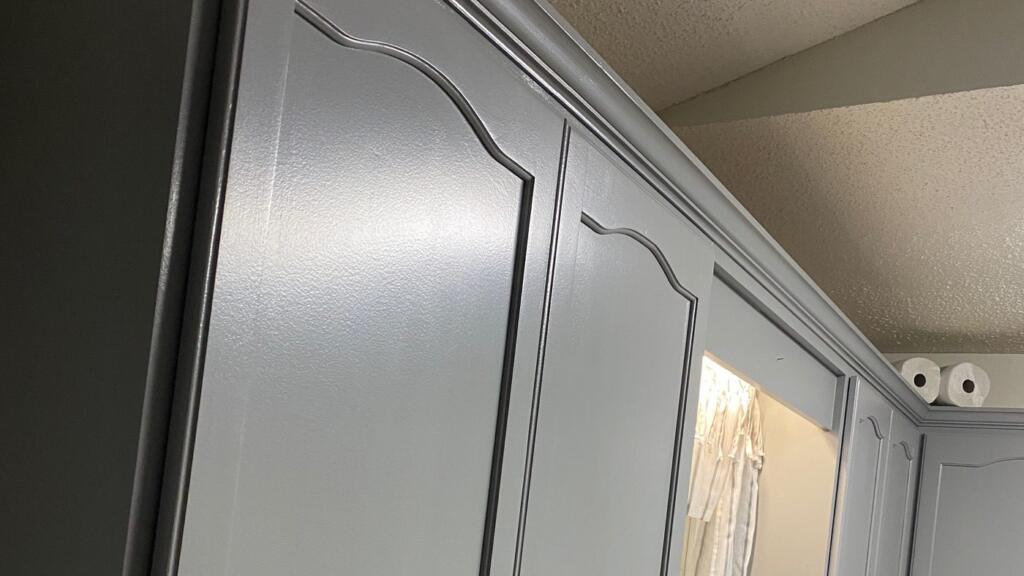 A close view of painted kitchen wall cabinets with arched door panels and dark round knobs.