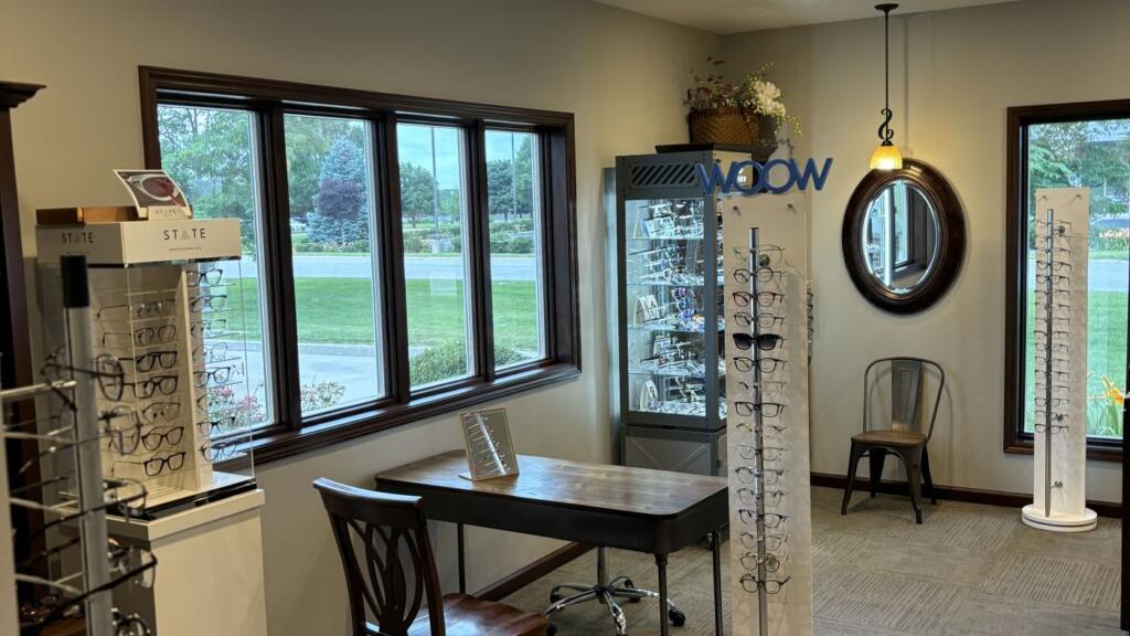 The interior of an eyewear shop with painted walls, dark window trim, recessed lighting and display racks along the floor.
